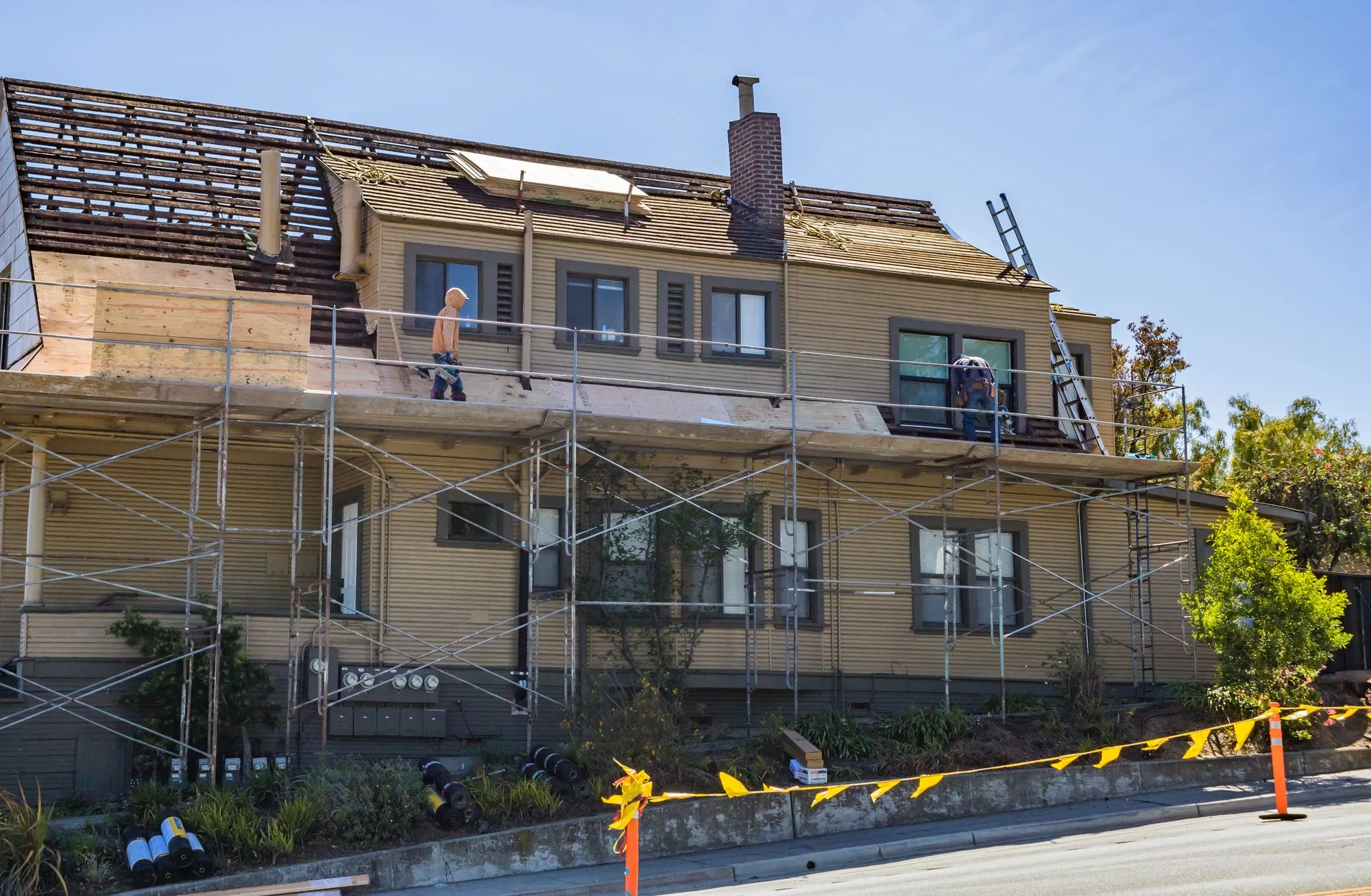 Scaffolding standing against a house while work goes on at the roofline