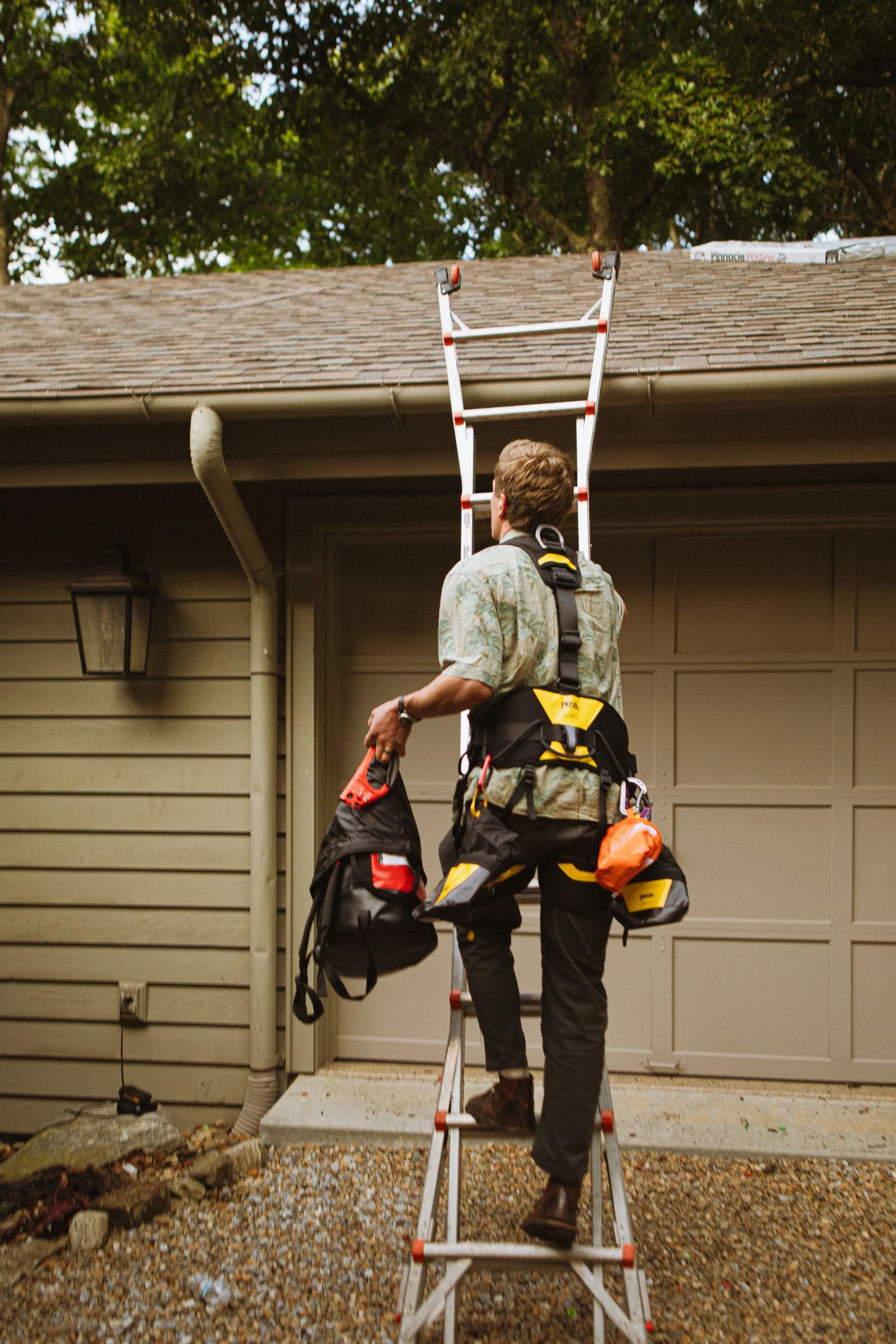 A roofer in a safety harness carrying his tool bag to the job