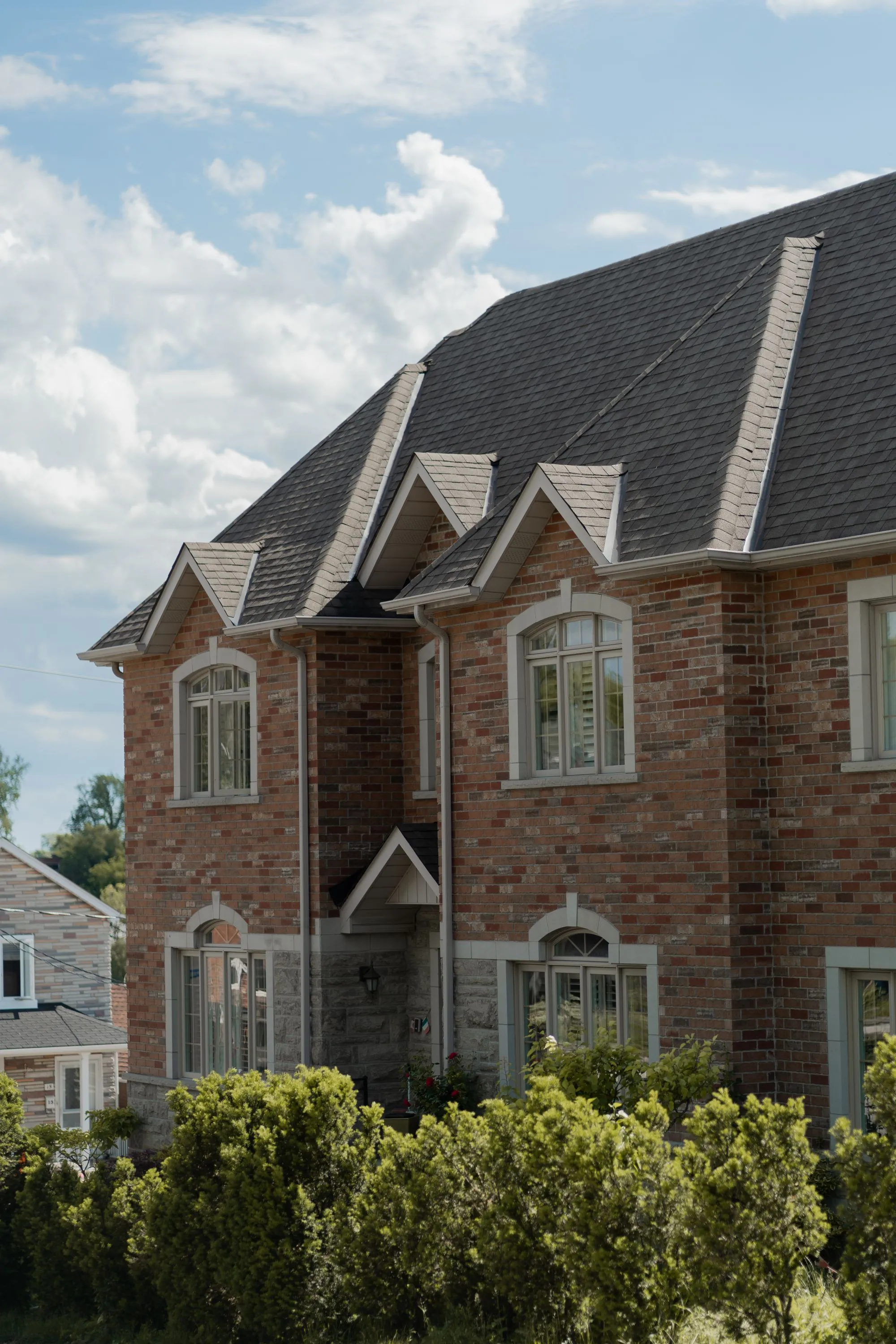 A brick house with steep shingled gables and dormer windows
