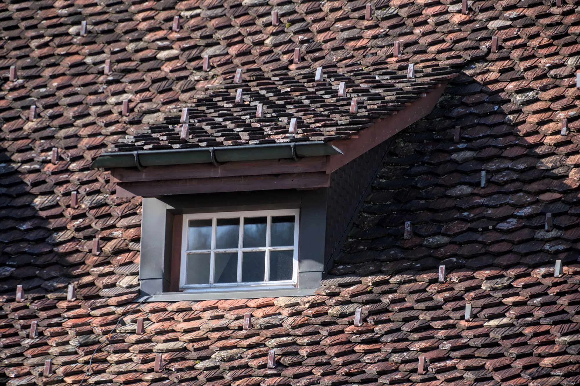 A dormer window set into an old roof covering