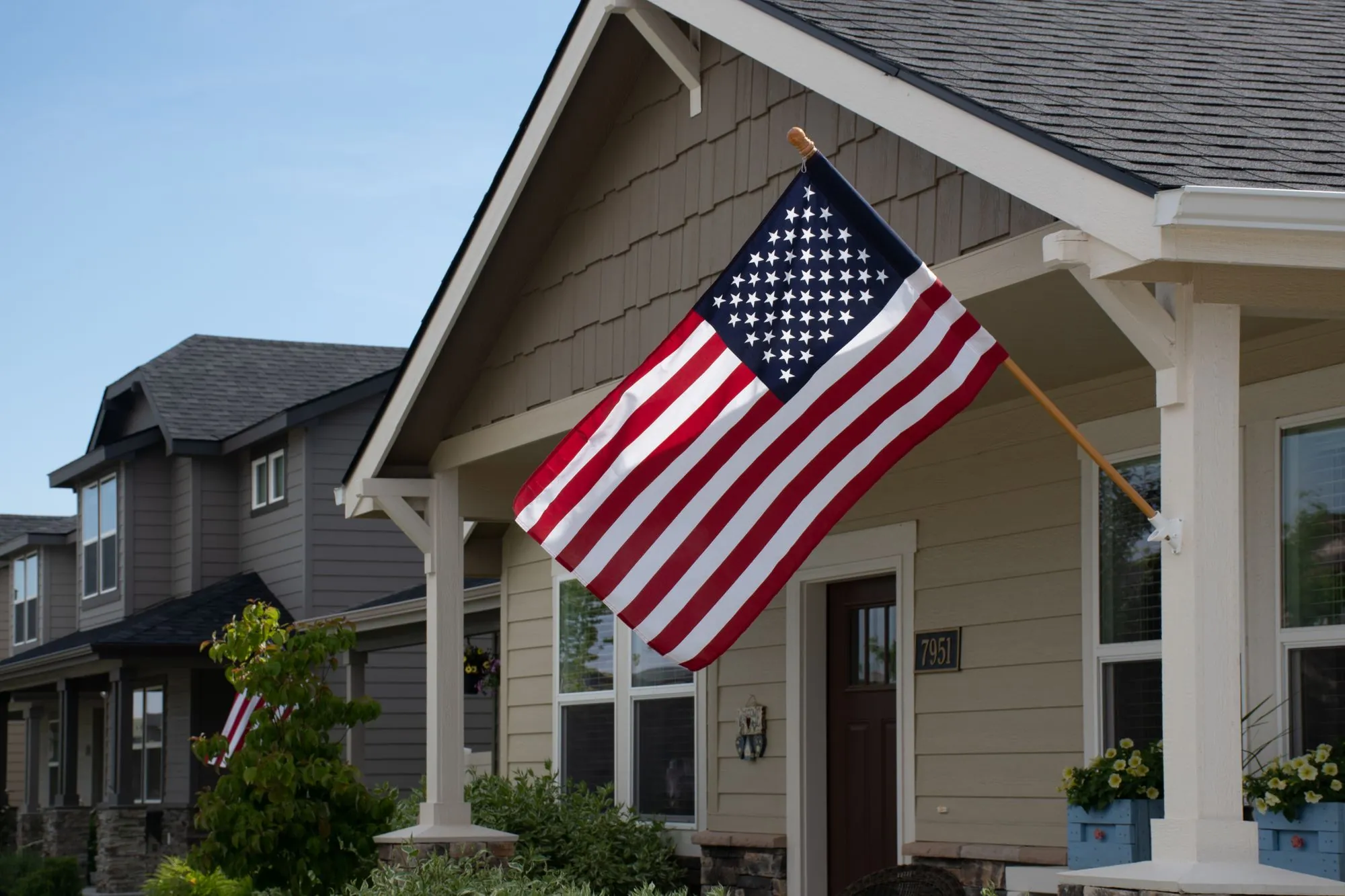 A front porch with a flag, on a street of neighbouring houses