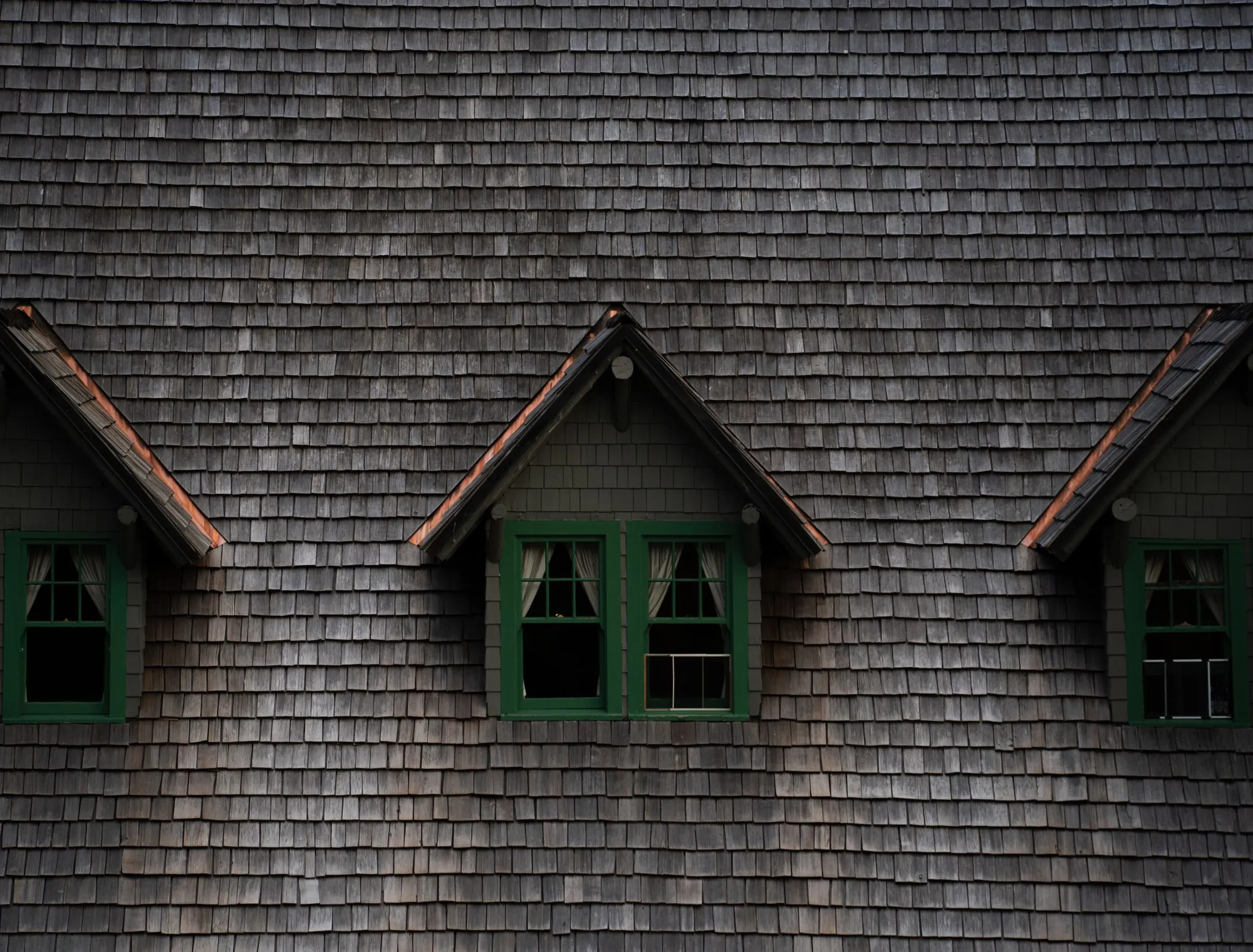 Dormers clad in shingle siding on a steep roof