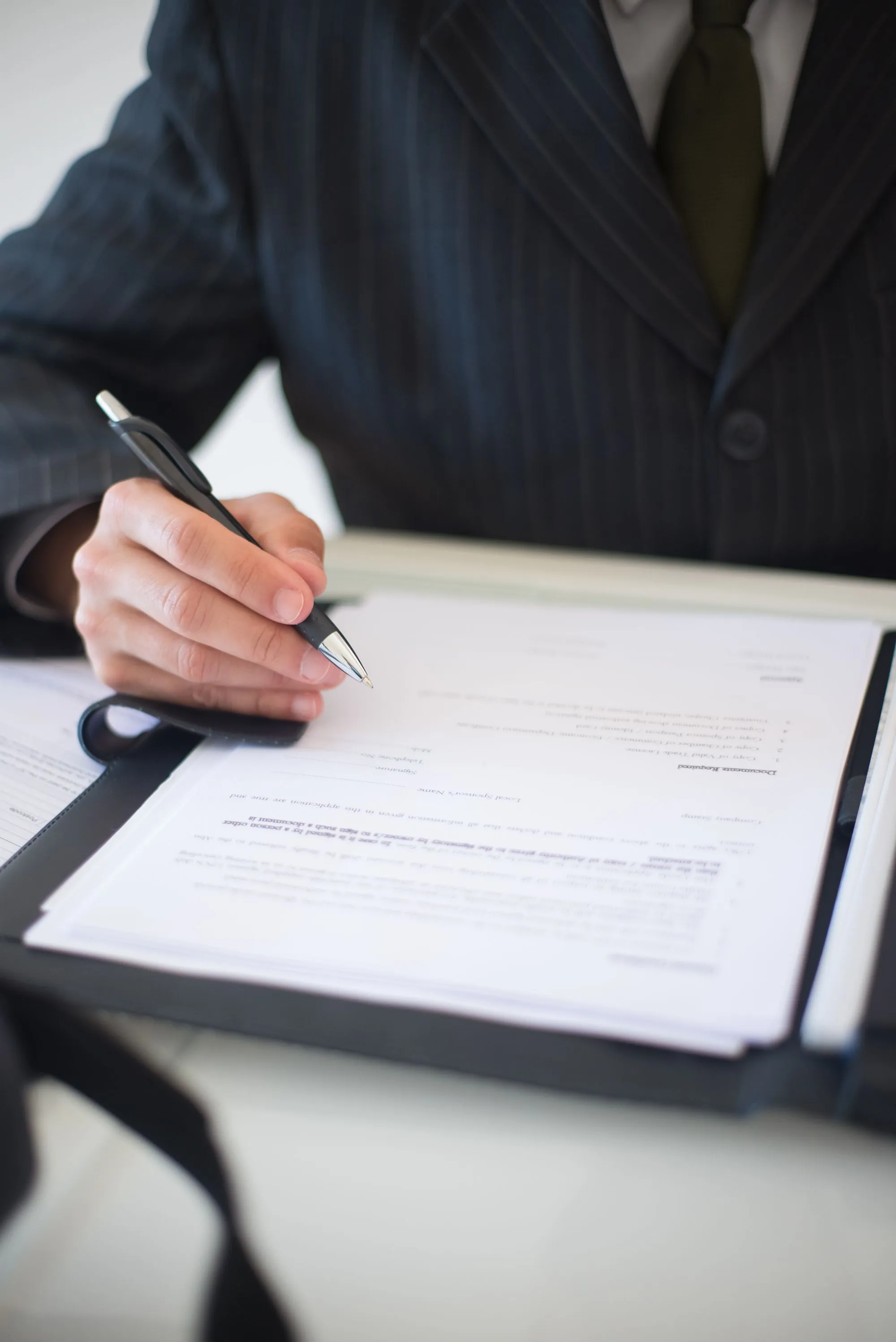 A hand writing on a document held on a clipboard